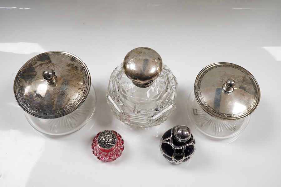 Two George V silver mounted glass powder jars, Henry Matthews, Birmingham, 1923, two silver mounted cut glass scent bottles including ruby flash and a white metal overlaid blue glass scent bottle.
